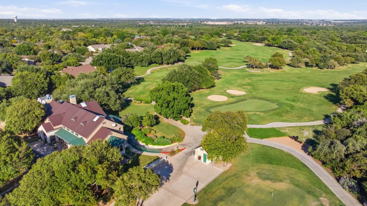 Aerial view of a Sun City Texas golf course and clubhouse among live oaks, Georgetown, TX